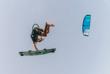 Load image into Gallery viewer, Person kite surfing with a blue Ozone Edge VT BIG AIR KITE against a clear sky
